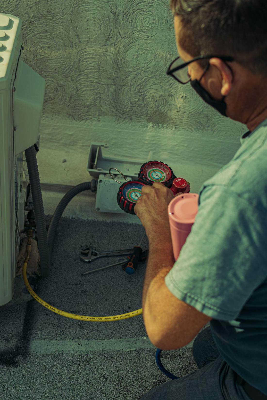 Technicien au manomètre sur une unité de climatisation